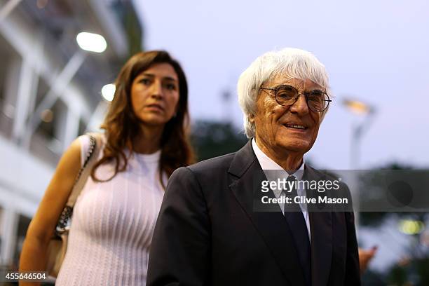 Supremo Bernie Ecclestone walks through the paddock with his wife Fabiana Flosi during previews ahead of the Singapore Formula One Grand Prix at...