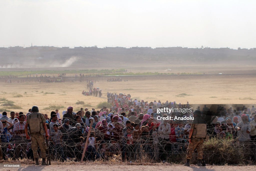 Syrians fleeing the war in their country wait to cross into Turkey