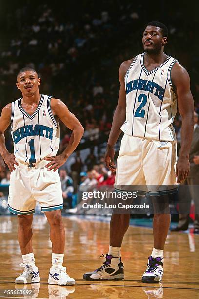 Larry Johnson and Muggsy Bogues of the Charlotte Hornets stand against the Los Angeles Clippers during a game played circa 1994 at the Charlotte...