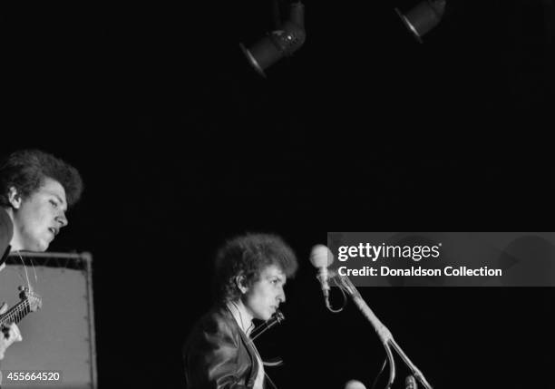 Bob Dylan plays a Fender Stratocaster electric guitar for the first time on stage as he performs at the Newport Folk Festival with guitarist Mike...