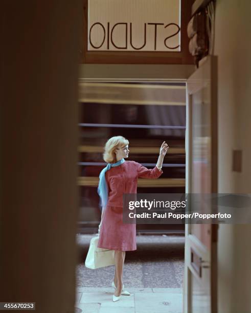 English model Jean Shrimpton poses in the doorway of a studio wearing a pink suede suit with a cardigan jacket, 1962.