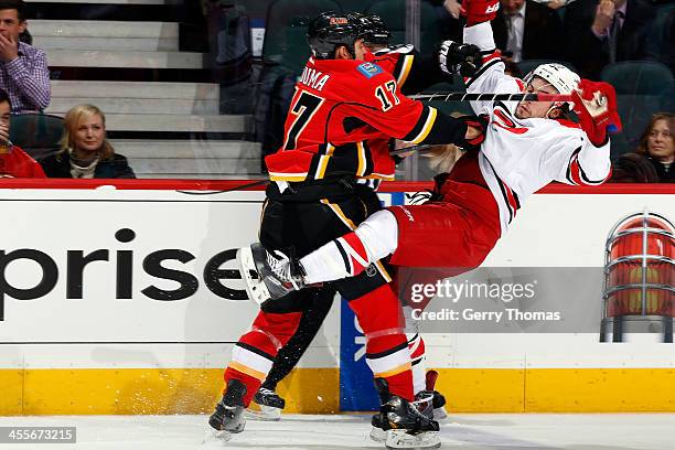 Lance Bouma of the Calgary Flames checks Justin Faulk of the Carolina Hurricanes at Scotiabank Saddledome on December 12, 2013 in Calgary, Alberta,...