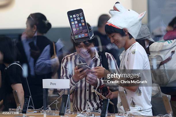 Customers look at the new iPhones on display at the launch of the new Apple iPhone 6 and iphone 6 plus at the Apple Omotesando store on September 19,...