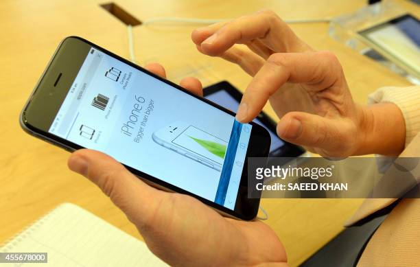 Woman checks the features of the new iPhone 6 at the Apple flagship store in Sydney on September 19, 2014. Hundreds of people queued through the...