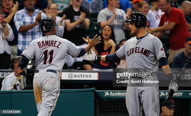 Jose Ramirez of the Cleveland Indians is greeted by teammate Mike Aviles after Ramirez scored a run against the Houston Astros in the ninth inning...