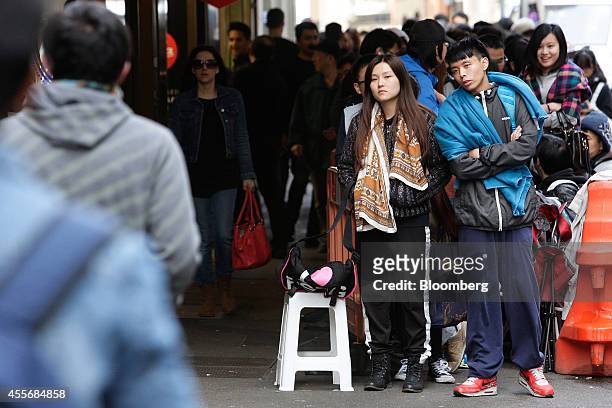 Customers wait in line to enter the Apple Inc. George Street store during the sales launch of the iPhone 6 and iPhone 6 Plus in Sydney, Australia, on...
