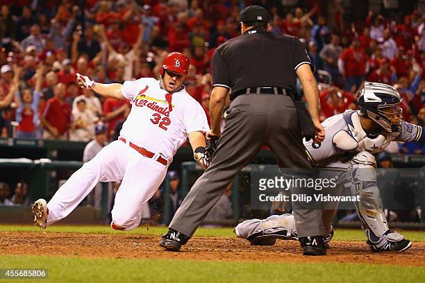 Matt Adams of the St. Louis Cardinals scores the game-winning run in the 13th inning against the Milwaukee Brewers at Busch Stadium on September 18,...