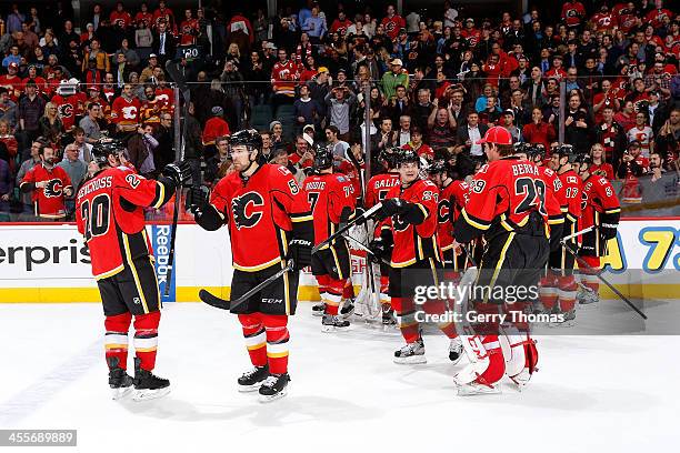 Curtis Glencross, David Jones and teammates of the Calgary Flames celebrate a win over the Carolina Hurricanes at Scotiabank Saddledome on December...