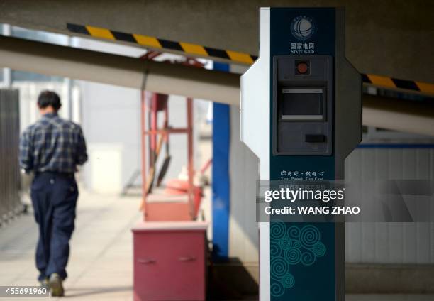 Man walks past a charging pile at a charging station under a overpass in Beijing on September 19, 2014. Chinese cities are plagued by heavy air...