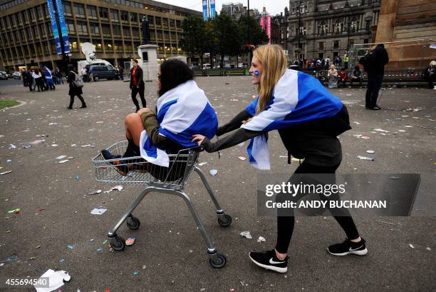 Pro-independence supporters push each other in a shopping trolley in Glasgow, Scotland, on September 19 following a defeat in the referendum on...