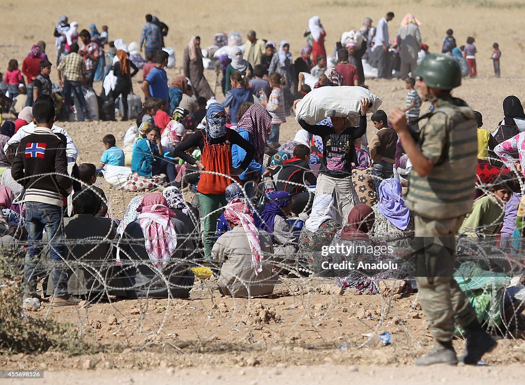 Syrians fleeing the war in their country wait to cross into Turkey