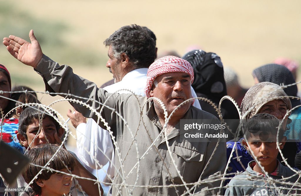 Syrians fleeing the war in their country wait to cross into Turkey