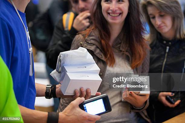 An employee, left, holds packaged iPhones as customers purchase the new smartphones during the sales launch of the iPhone 6 and iPhone 6 Plus at the...