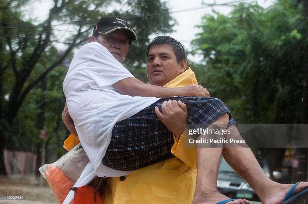 A man carries an elderly person while evacuating the flooded...