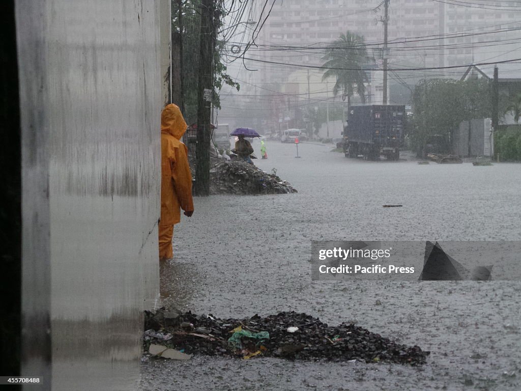 Men passing thru flooded Panay Avenue in Quezon City as...