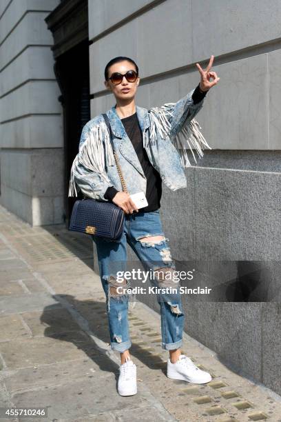 Model Sissi Hou is wearing a Chanel bag, Nike shoes, Urban Outfitters jeans, and vintage sunglasses and jacket on day 3 of London Collections: Women...