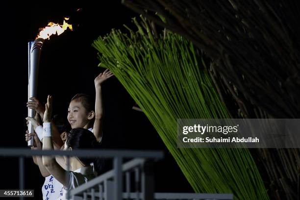 Young torch bearer prepares to light up the cauldron during the Opening Ceremony ahead of the 2014 Asian Games at Incheon Asiad Main Stadium on...