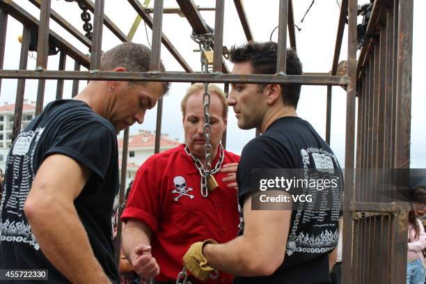 Canadian escape artist Dean Gunnarson performs cage escape over a lake on September 19, 2014 in Zhangjiajie, China.