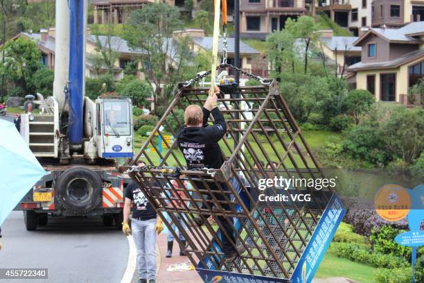 Canadian escape artist Dean Gunnarson performs cage escape over a lake on September 19, 2014 in Zhangjiajie, China.