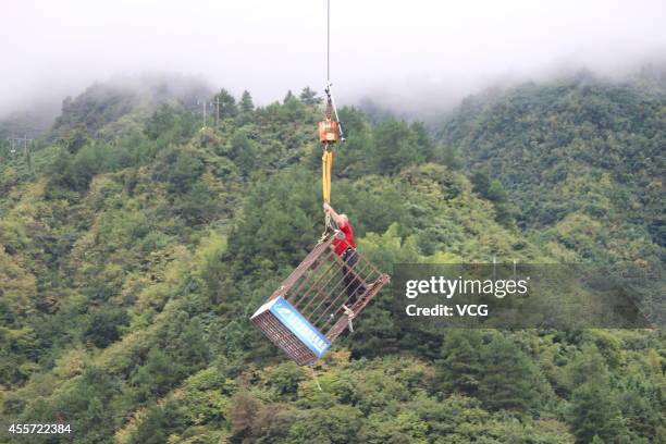 Canadian escape artist Dean Gunnarson performs cage escape over a lake on September 19, 2014 in Zhangjiajie, China.