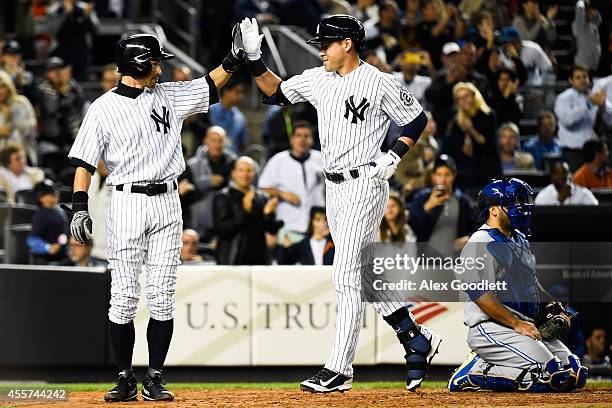 Ichiro Suzuki and Jacoby Ellsbury of the New York Yankees high five after scoring in the third inning against the Toronto Blue Jays at Yankee Stadium...