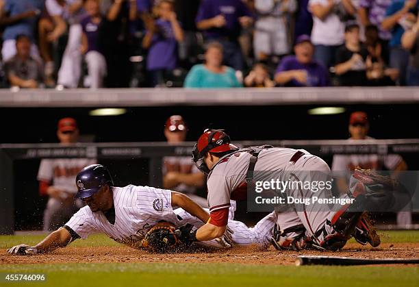 Rafael Ynoa of the Colorado Rockies attempts to stretch his two RBI triple into an inside the park home run and is tagged out by catcher Miguel...