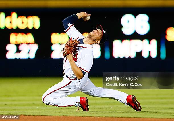 Andrelton Simmons of the Atlanta Braves attempts to make a play on a single hit by Wilmer Flores of the New York Mets in the ninth inning at Turner...
