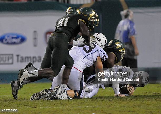 Connecticut's Chandler Whitmer is brought down by South Florida's Derrick Calloway in the second half at Raymond James Stadium in Tampa, Fla., on...