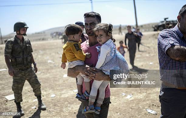 Syrian Kurd carries children in his arms after crossing the border between Syria and Turkey near the southeastern town of Suruc in Sanliurfa...