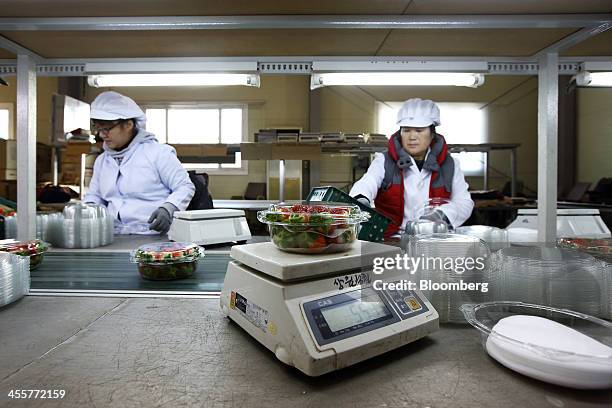 Package of strawberries sits on an electronic scale as workers pack strawberries and place them on a conveyor at a packing warehouse, operated by the...