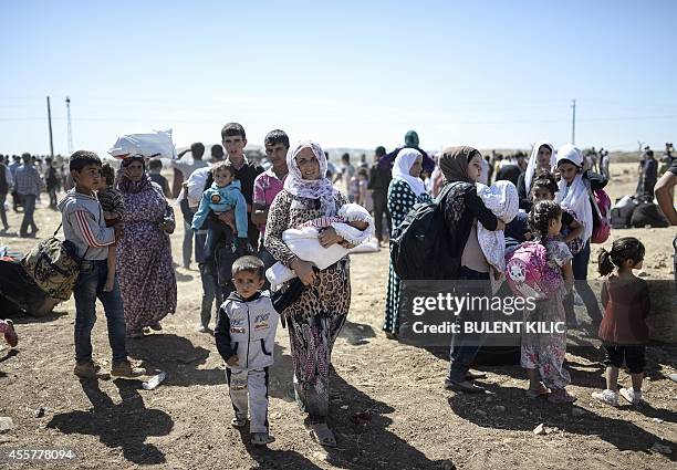 Syrian Kurds carry their belongings on September 20, 2014 after crossing the border from Syria into Turkey near the southeastern town of Suruc in...