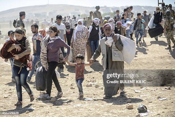 Syrian Kurds wait to cross on September 20, 2014 the border from Syria into Turkey near the southeastern town of Suruc in Sanliurfa province. Tens of...