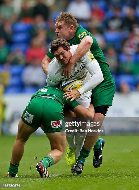 Alex Goode of Saracens is tackled by Scott Steele and Blair Cowan of London Irish during the Aviva Premiership match between London Irish and...