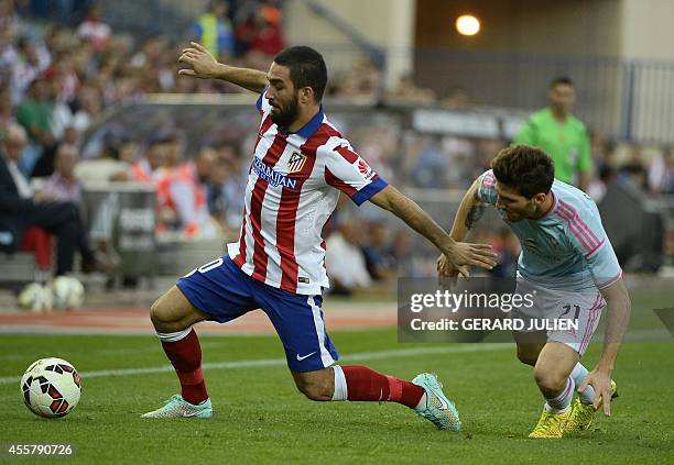 Atletico Madrid's Turkish midfielder Arda Turan vies with Celta Vigo's defender Carles Planas during the Spanish league football match Club Atletico...