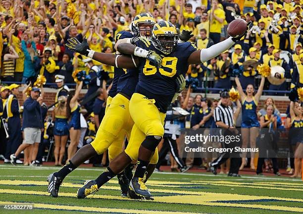 Willie Henry of the Michigan Wolverines celebrates a second quarter interception for a touchdown with Mario Ojemudia and Brennen Beyer while playing...