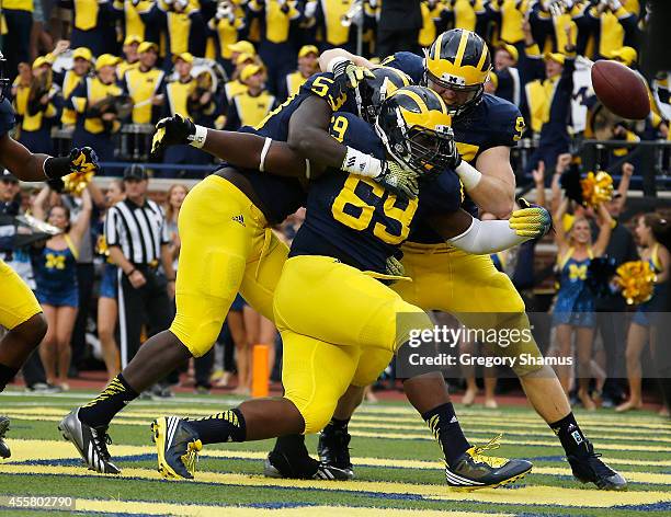 Willie Henry of the Michigan Wolverines celebrates a second quarter interception for a touchdown with Mario Ojemudia and Brennen Beyer while playing...