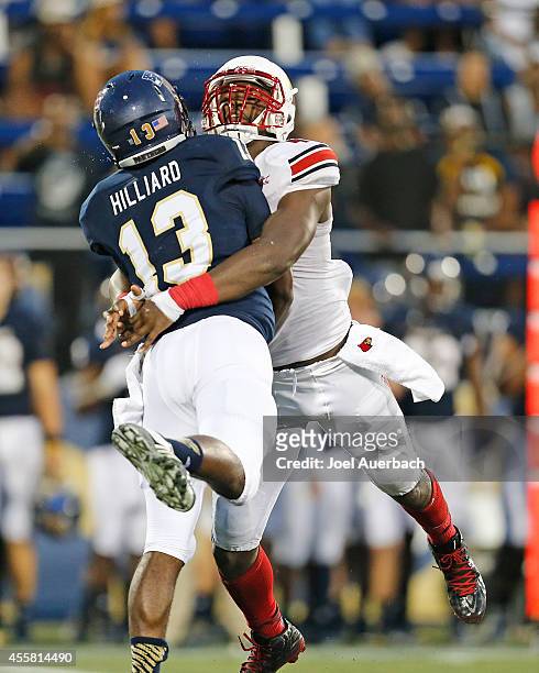 Deiontrez Mount of the Louisville Cardinals wraps up E.J. Hilliard of the Florida International Panthers as he releases the ball on September 20,...
