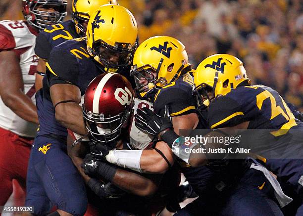 Samaje Perine of the Oklahoma Sooners is stopped by Brandon Golson and Ishmael Banks of the West Virginia Mountaineers in the first half during the...