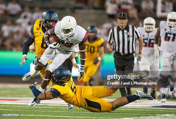 Wide receiver Davonte' Neal of the Arizona Wildcats holds on to the catch while being tackled by safety Michael Lowe of the California Golden Bears...