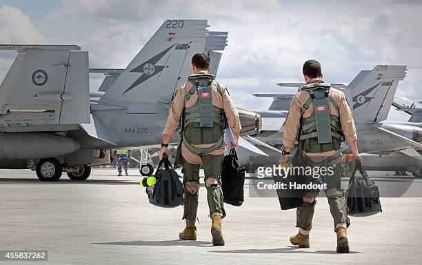 In this handout image provided by Commonwealth of Australia, F/A-18F Super Hornet aircrew head to their aircraft in preparation for departure to the...