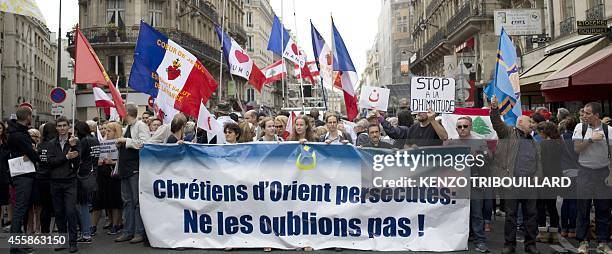 Demonstrators hold a banner reading "Don't forget the persecuted Christians in the Middle East" on September 21, 2014 in Paris during a rally called...