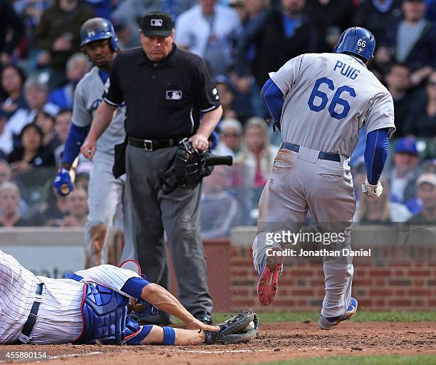 Home plate umpire Gerry Davis watches as Yasiel Puig of the Los Angeles Dodgers avoids the tag attempt by Welington Castillo of the Chicago Cubs to...