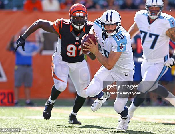 Jake Locker of the Tennessee Titans scrambles away from Robert Geathers of the Cincinnati Bengals during the fourth quarter at Paul Brown Stadium on...