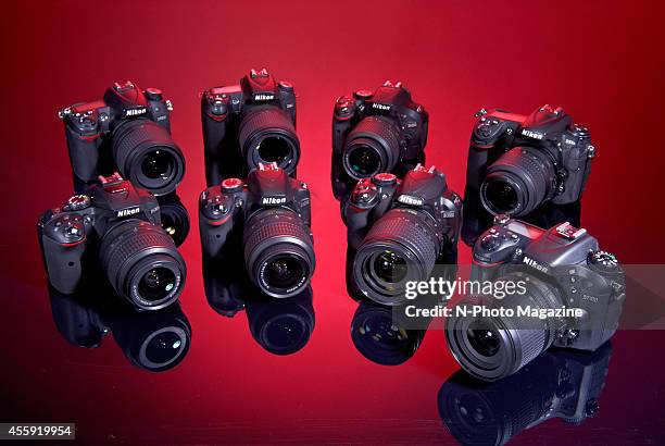 Selection of DX-format Nikon DSLR cameras photographed on a red background, including D7000, D90, D5200, D300s, D3100, D3200 and D5300 models, taken...