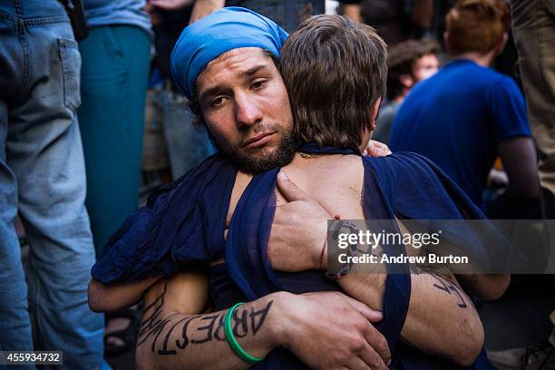 Two protesters hold each other after clashing with police while trying to walk down Wall Street towards the New York Stock Exchange on September 22,...