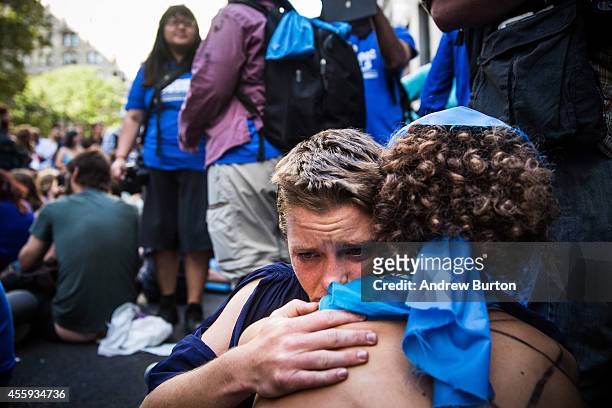 Two protesters hold each other after clashing with police while trying to walk down Wall Street towards the New York Stock Exchange on September 22,...