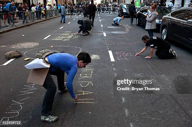 Demonstrators use chalk to write messages on Broadway during the Flood Wall Street protest on September 22, 2014 in New York City. The Flood Wall...