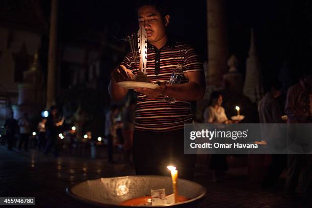 Man carries a plate holding rice, fruit and paper cut outs while circling the main pagoda three times as a tradition during Pchum Ben festival in Wat...