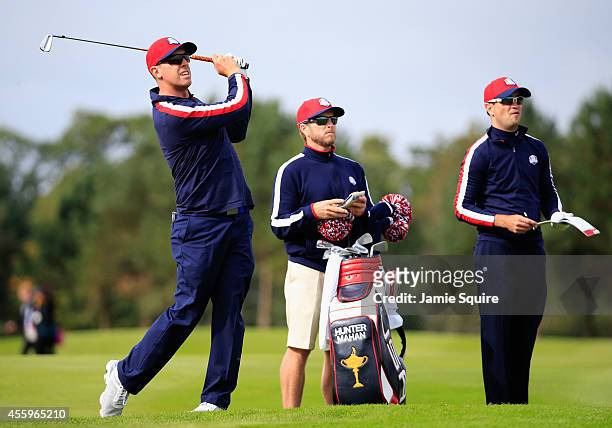 Hunter Mahan of the United States hits an iron with caddie John Wood and Zach Johnson of the United States during practice ahead of the 2014 Ryder...
