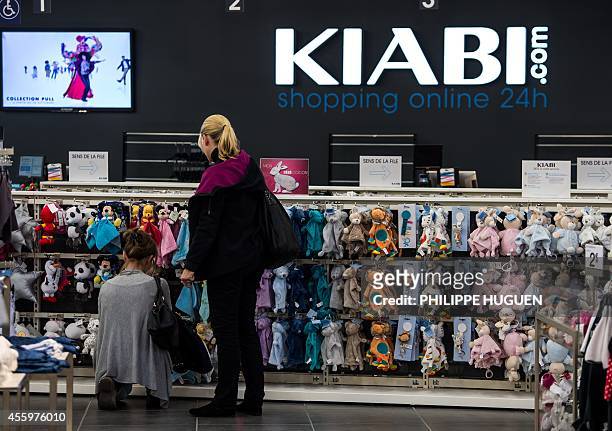 Customers look at clothes in a shop of French clothing company Kiabi in Faches-Thumesnil, northern France, on September 23, 2014. AFP PHOTO /...